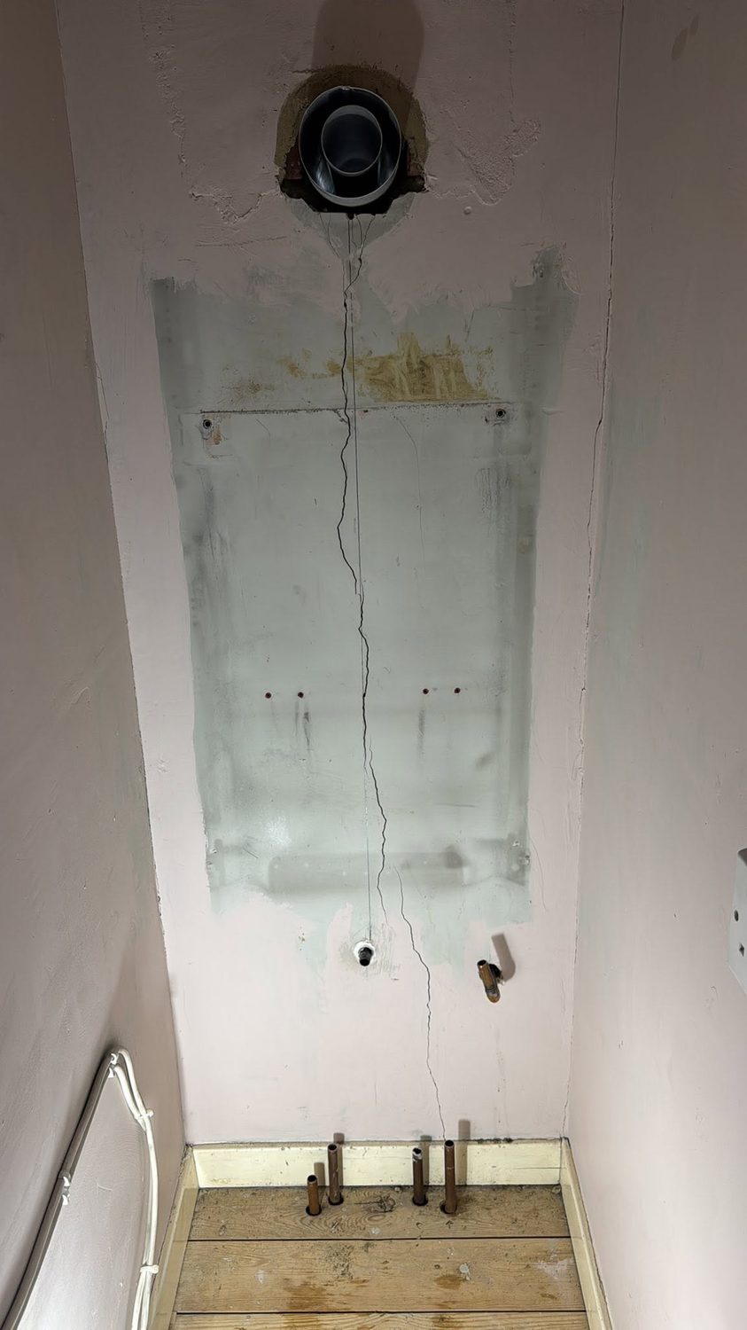 Stripped wall and old pipework before the boiler install